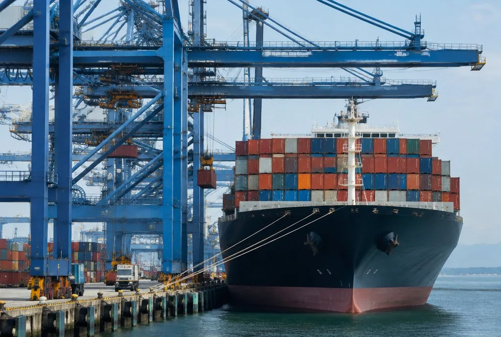 container ship being loaded at a huge port with gantry cranes